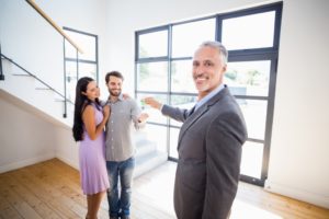 broker giving happy couple the keys to their new home