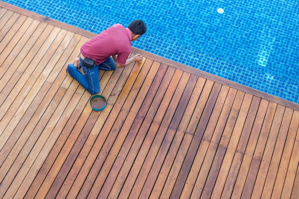 man cleaning the deck floor beside the pool