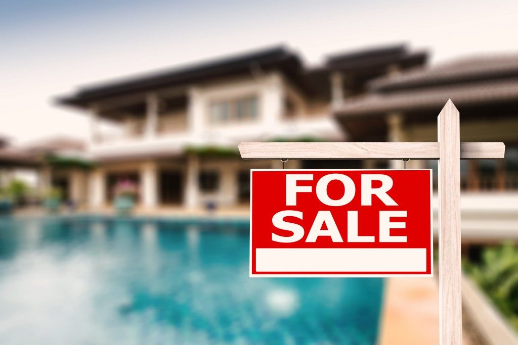 For sale sign at luxury house with pool background