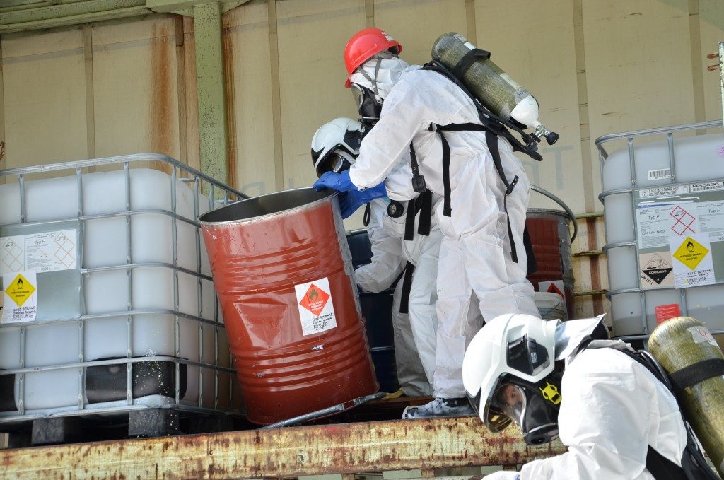 Professionals wearing safety gear while handling hazardous chemicals