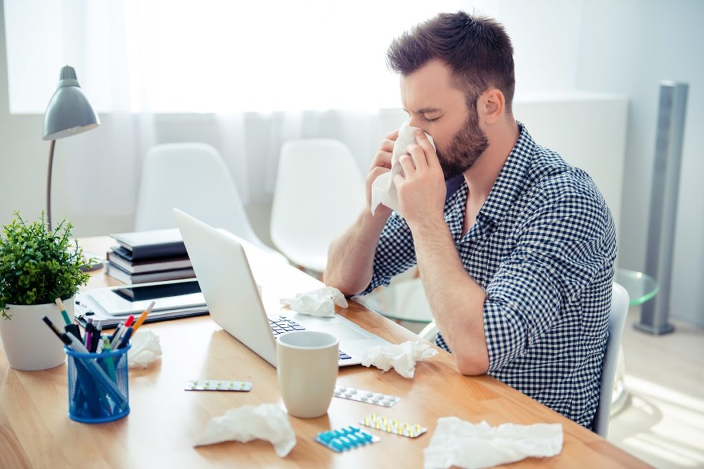Man sneezing at his desk