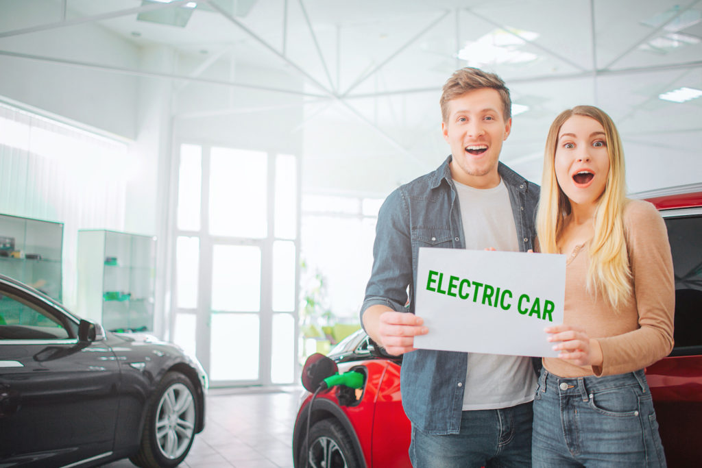 Couple holding electric vehicle sign