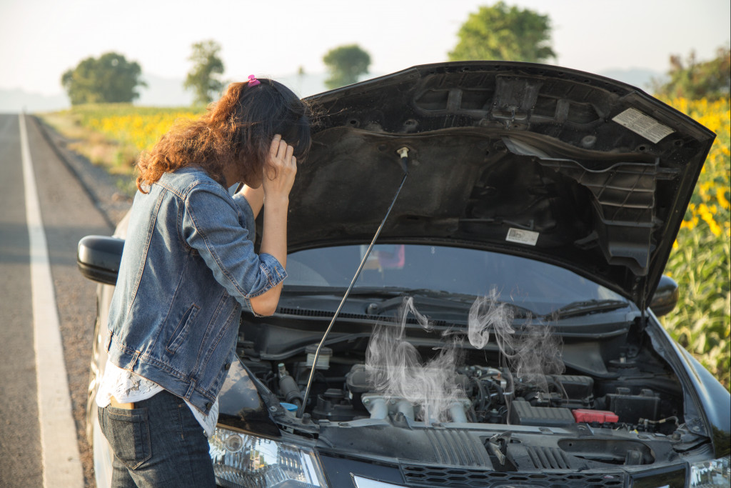 woman checking her car engine due to overheat