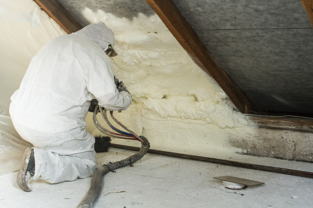 A working spraying insulating foam on the attic ceiling